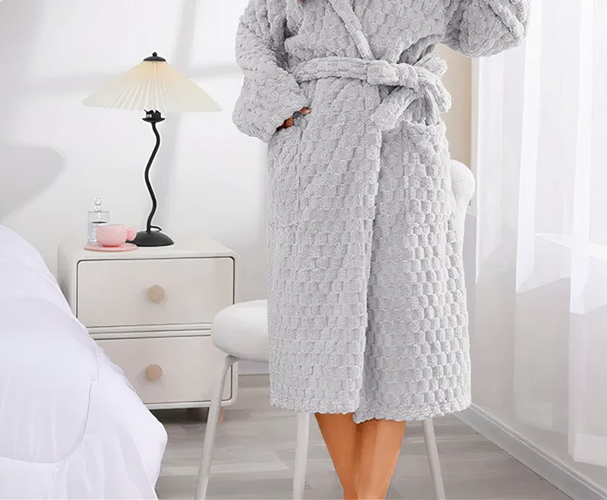 Le coloris gris clair porté debout : la ceinture nouée à la taille, une main glissée dans la poche et l’ourlet qui tombe sous le genou