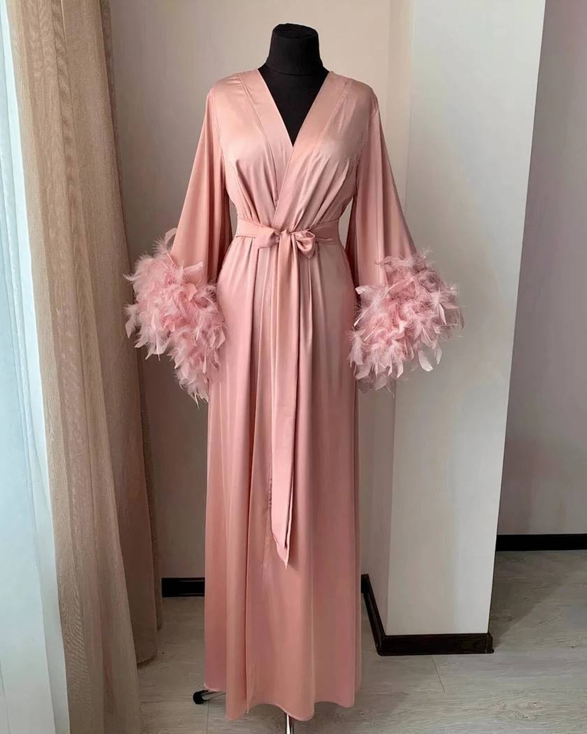 Le peignoir en rose, plumes assorties au poignet