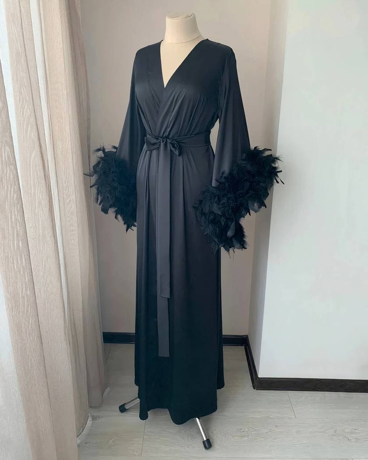 Le peignoir en noir, plumes noires au bas des manches