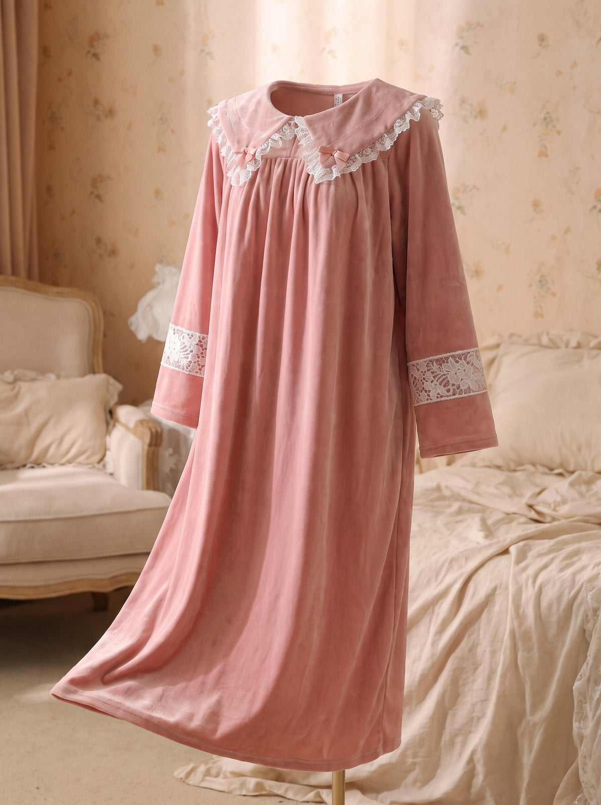 Robe de nuit princesse en velours rose presentee sur mannequin invisible, col Claudine dentelle blanche et noeuds roses, decor boudoir