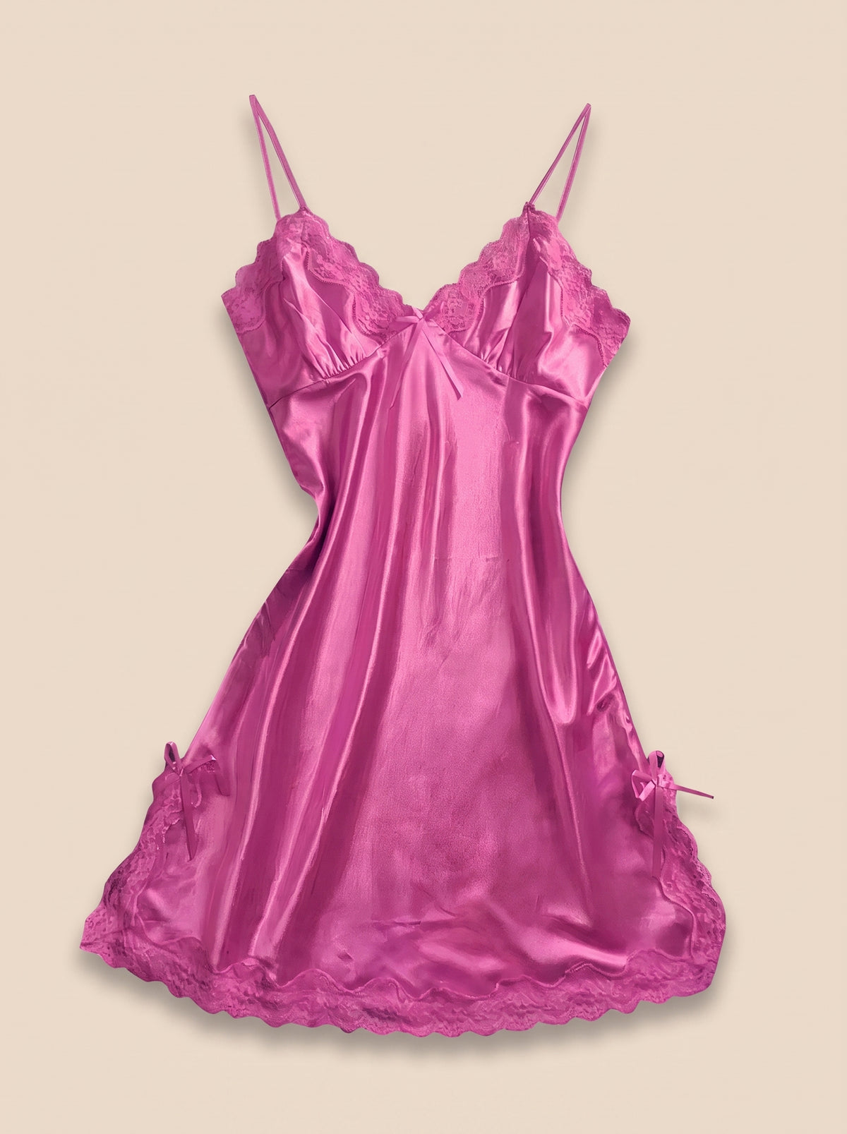 Nuisette en satin rose à dentelle et petits nœuds portée par mannequin invisible, vue de face