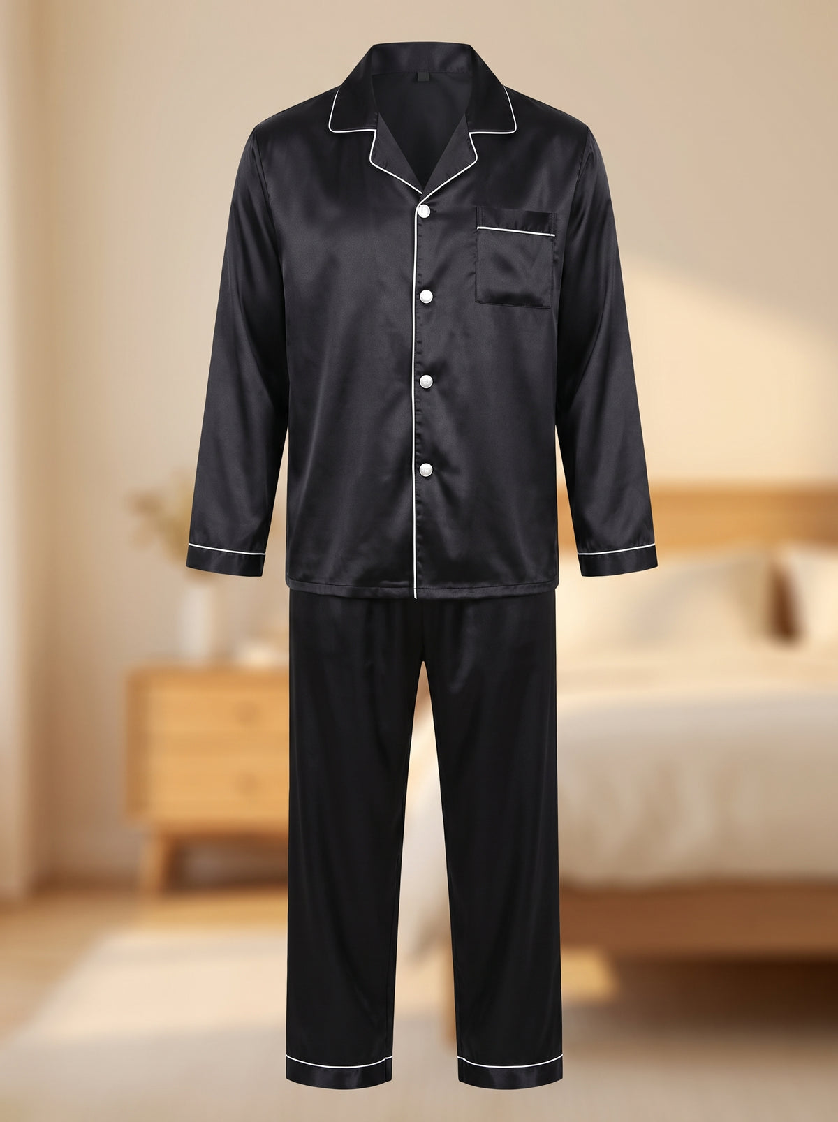 Ensemble de pyjama homme noir satiné présenté sans mannequin, chemise boutonnée à col cranté et pantalon droit, dans une chambre crème