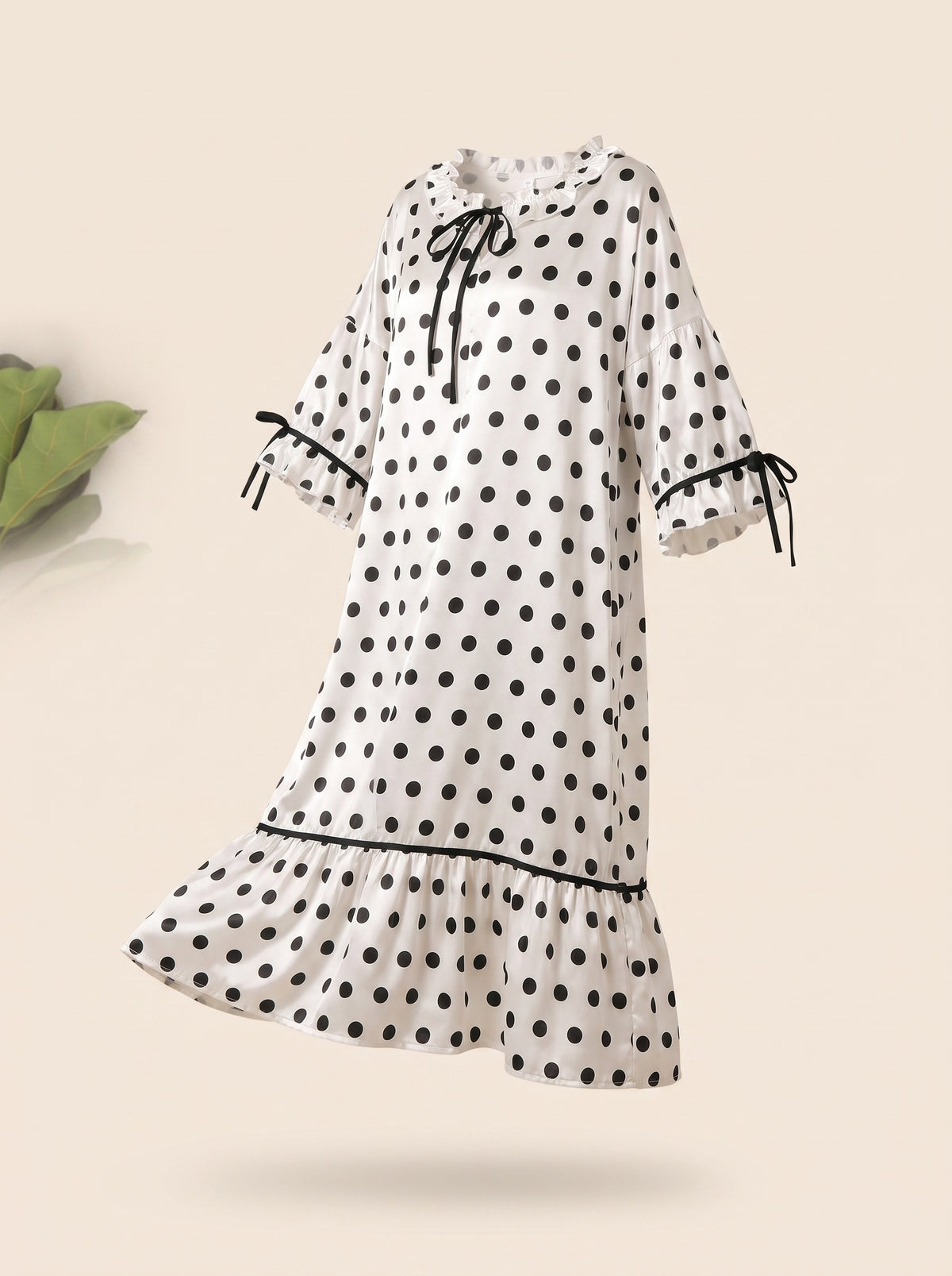 Nuisette longue blanche à pois noirs en satin portée par un mannequin invisible, vue de face