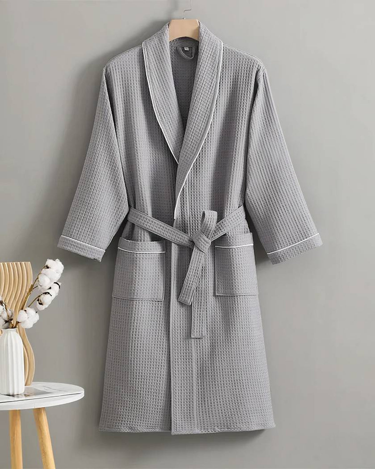 Peignoir en coton gaufré gris sur cintre, col châle à passepoil blanc et deux poches plaquées