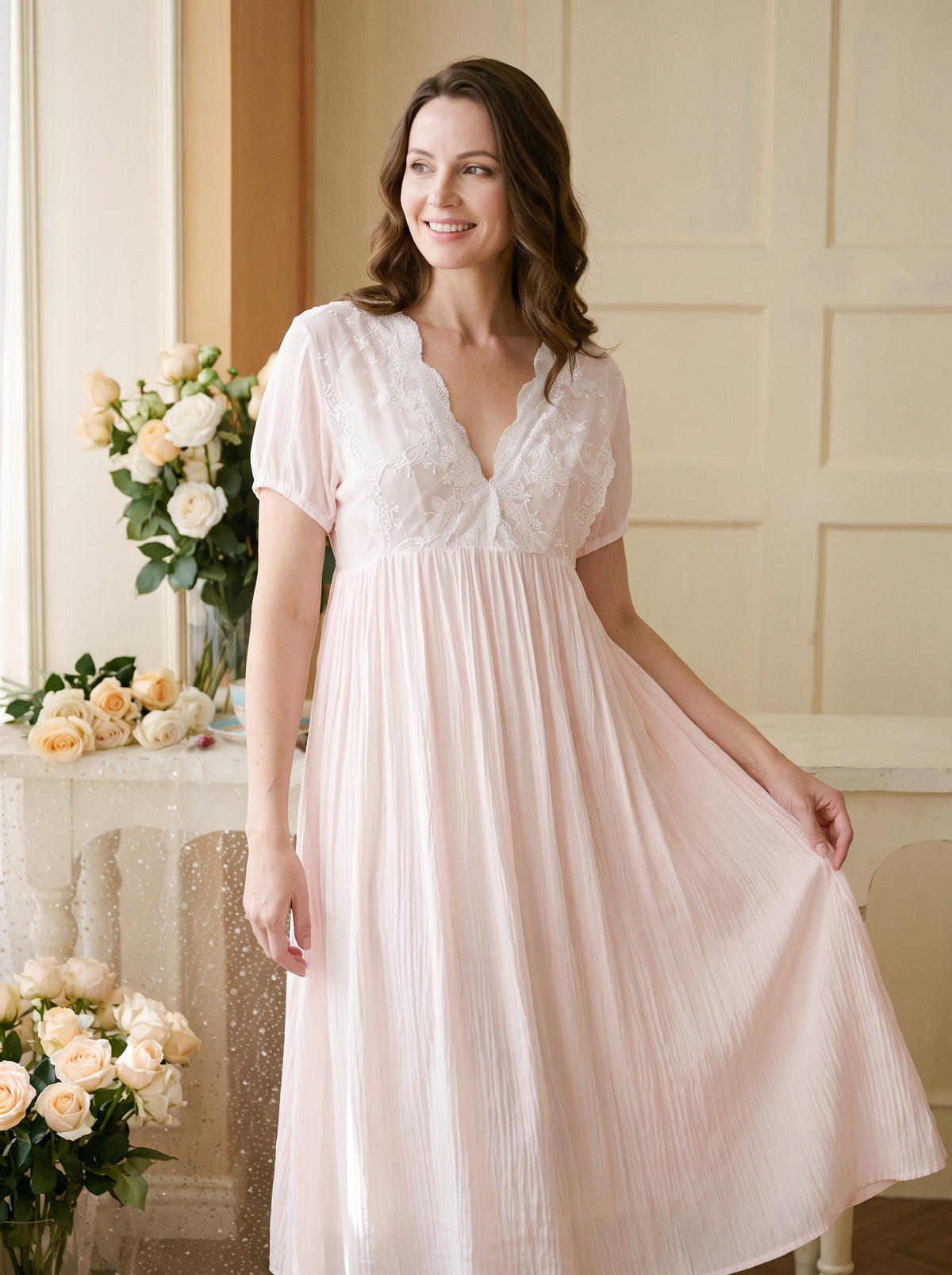 Femme souriante portant une chemise de nuit longue rose à plastron de dentelle blanche