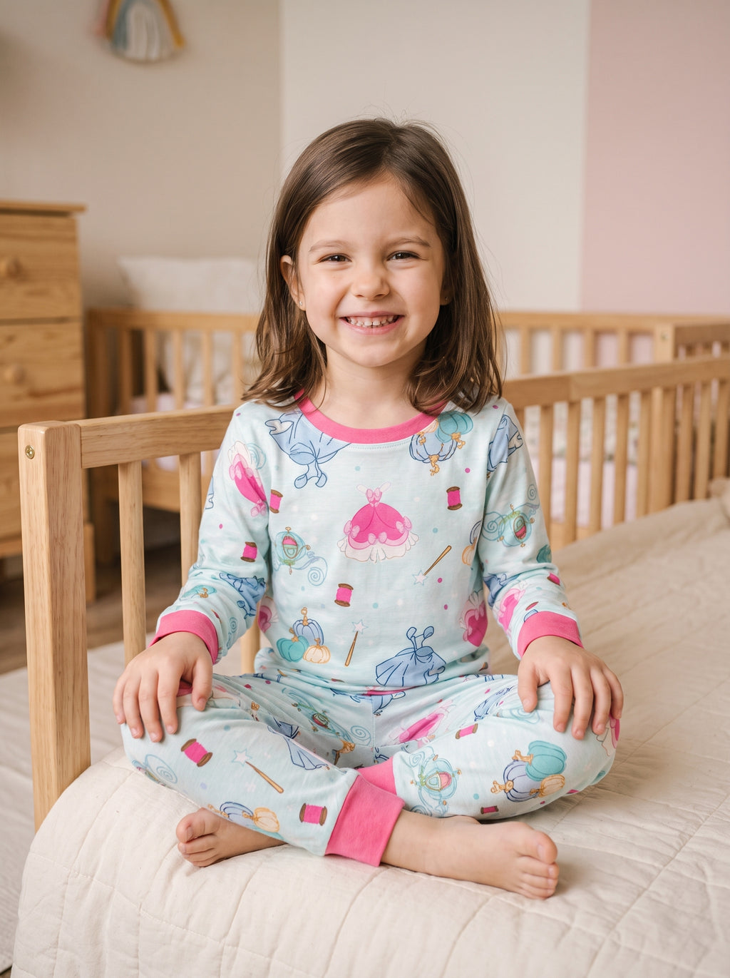 Petite fille assise en tailleur sur son lit, en pyjama princesse vert d'eau à manches longues et pantalon assorti
