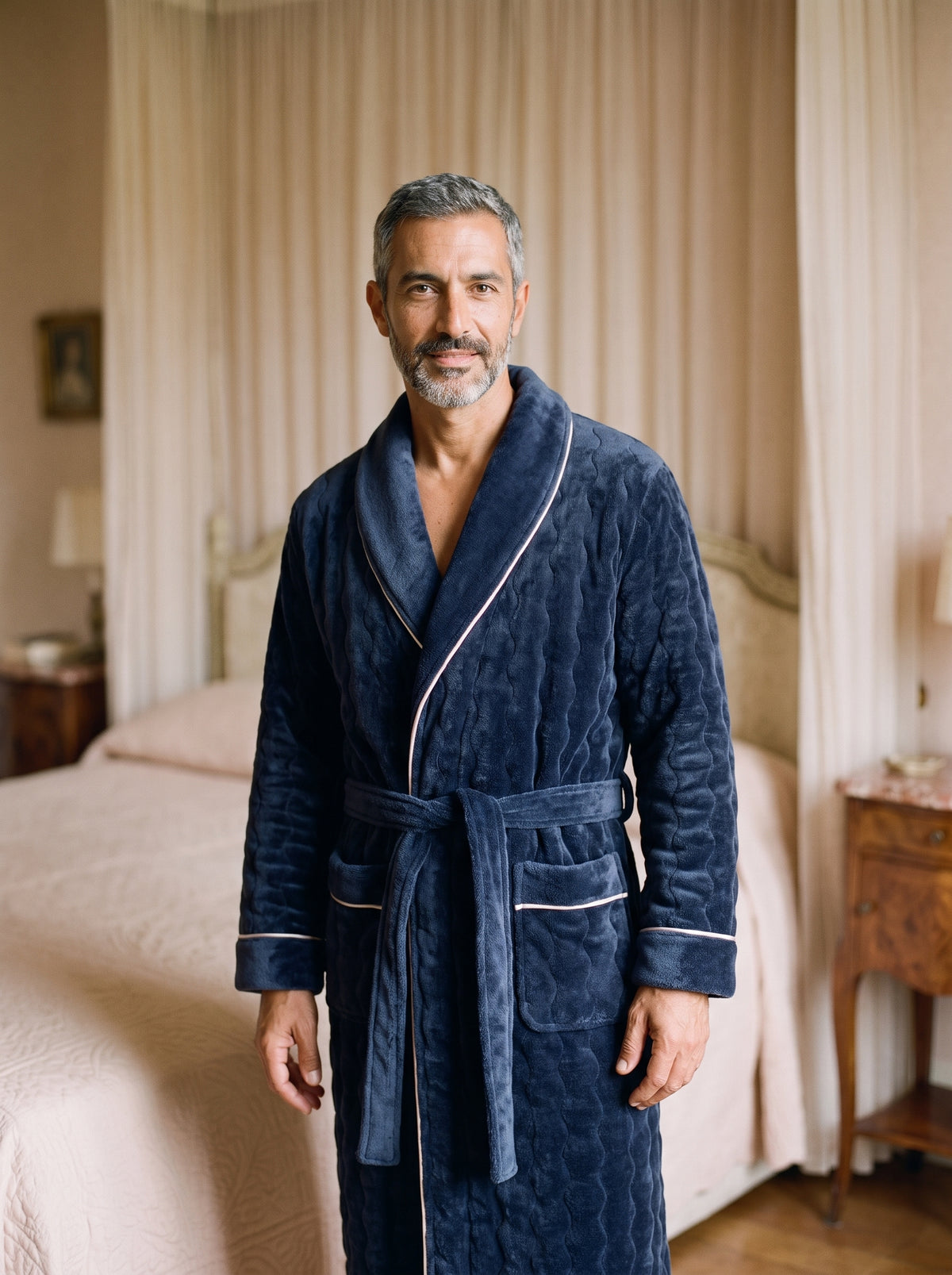 Homme debout en peignoir polaire bleu marine à col châle, la ceinture unie nouée à la taille et le liseré ivoire suivant le col et le devant