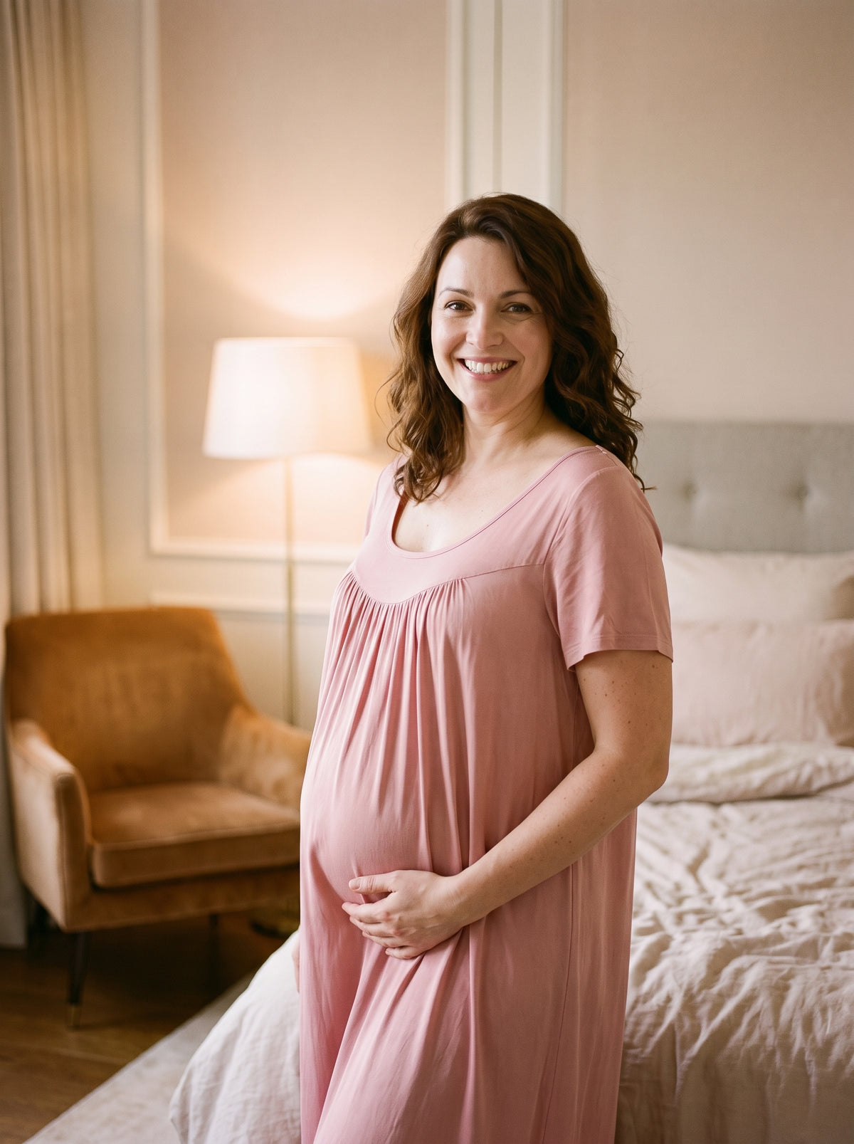 Femme enceinte souriante portant la chemise de nuit rose poudré en coton, encolure arrondie large et empiècement froncé