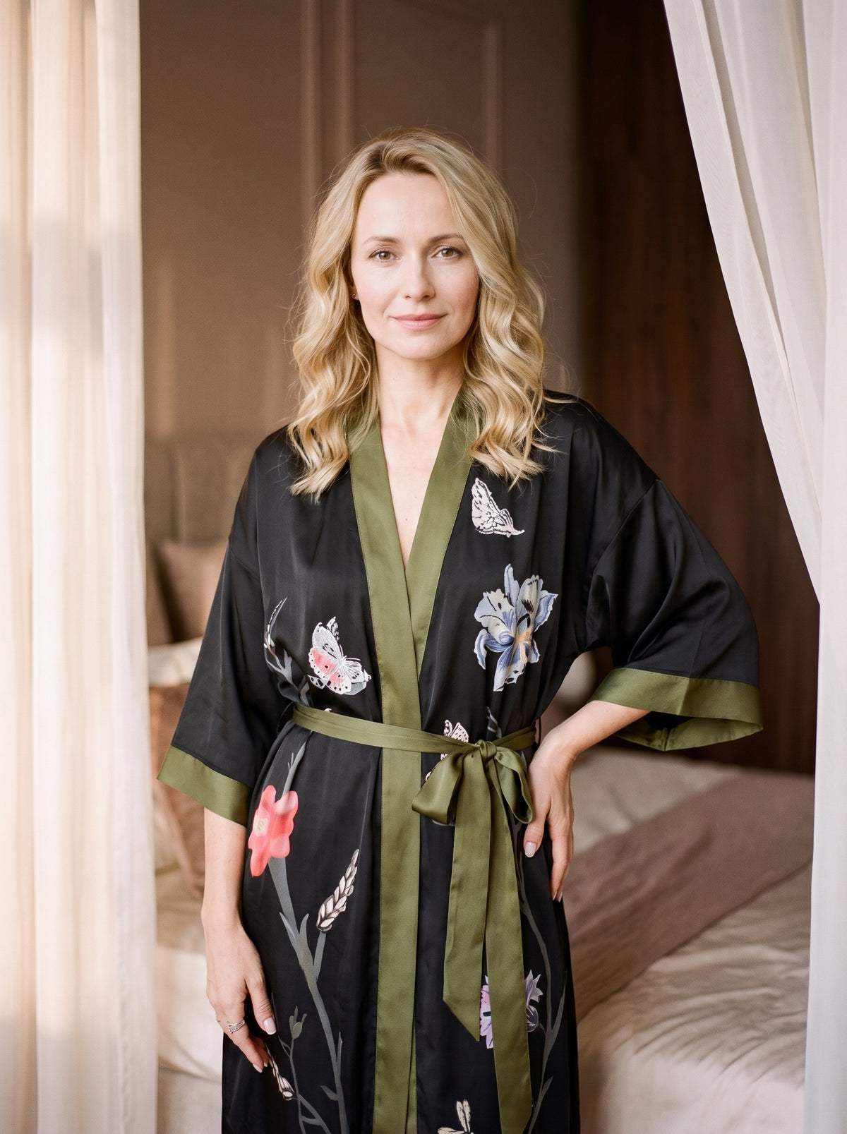 Femme debout en peignoir kimono noir à fleurs, une main posée sur la hanche à côté du nœud de ceinture vert kaki