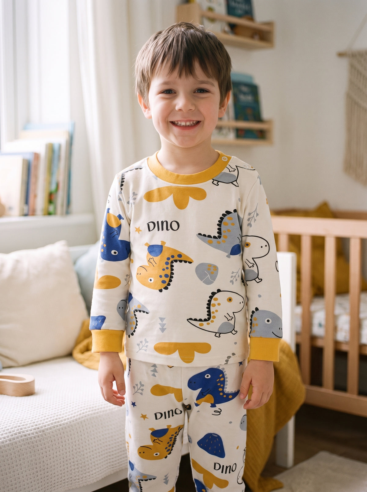 Petit garçon debout dans sa chambre en pyjama imprimé dinosaures, haut à manches longues et pantalon