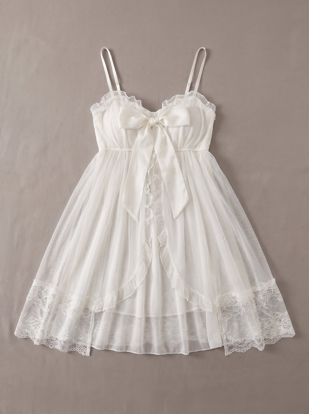Nuisette babydoll blanche à noeud devant posée à plat, tulle transparent romantique