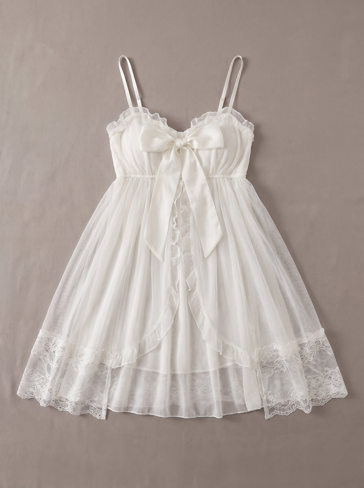 Nuisette babydoll blanche à noeud devant posée à plat, tulle transparent romantique