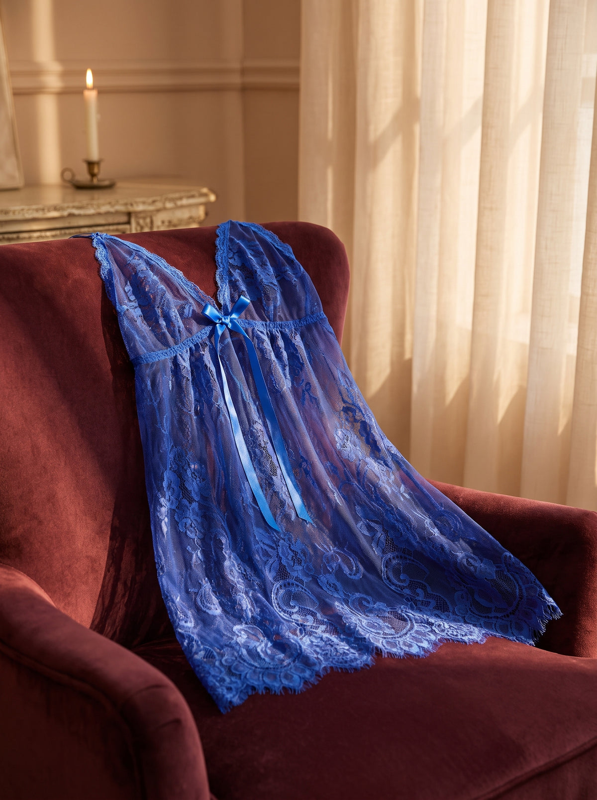Nuisette bleue en voile transparent drapee sur un fauteuil en velours bordeaux, ambiance boudoir