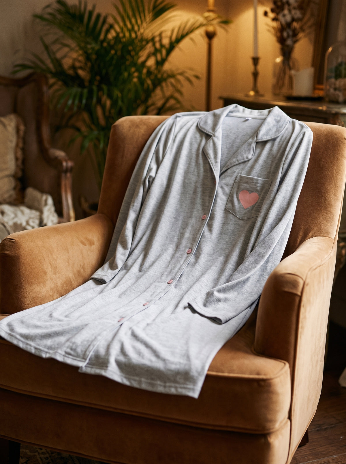 Chemise de nuit femme grise drapée sur un fauteuil en velours caramel dans un boudoir