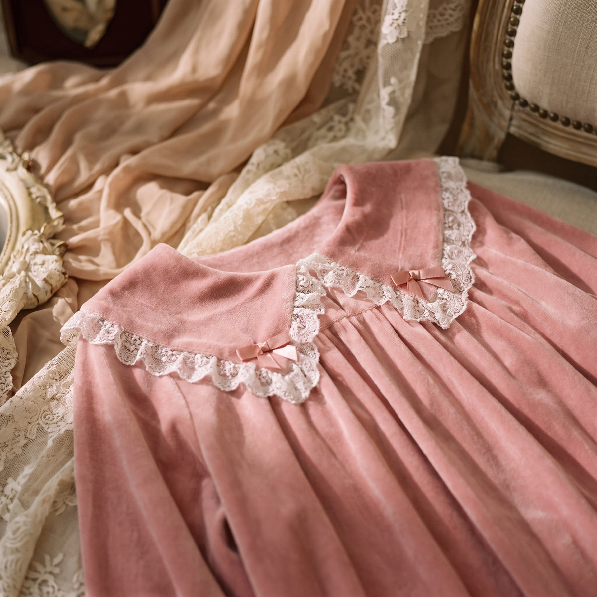 Gros plan sur le col Claudine en dentelle blanche et les noeuds en ruban rose de la robe de nuit princesse en velours