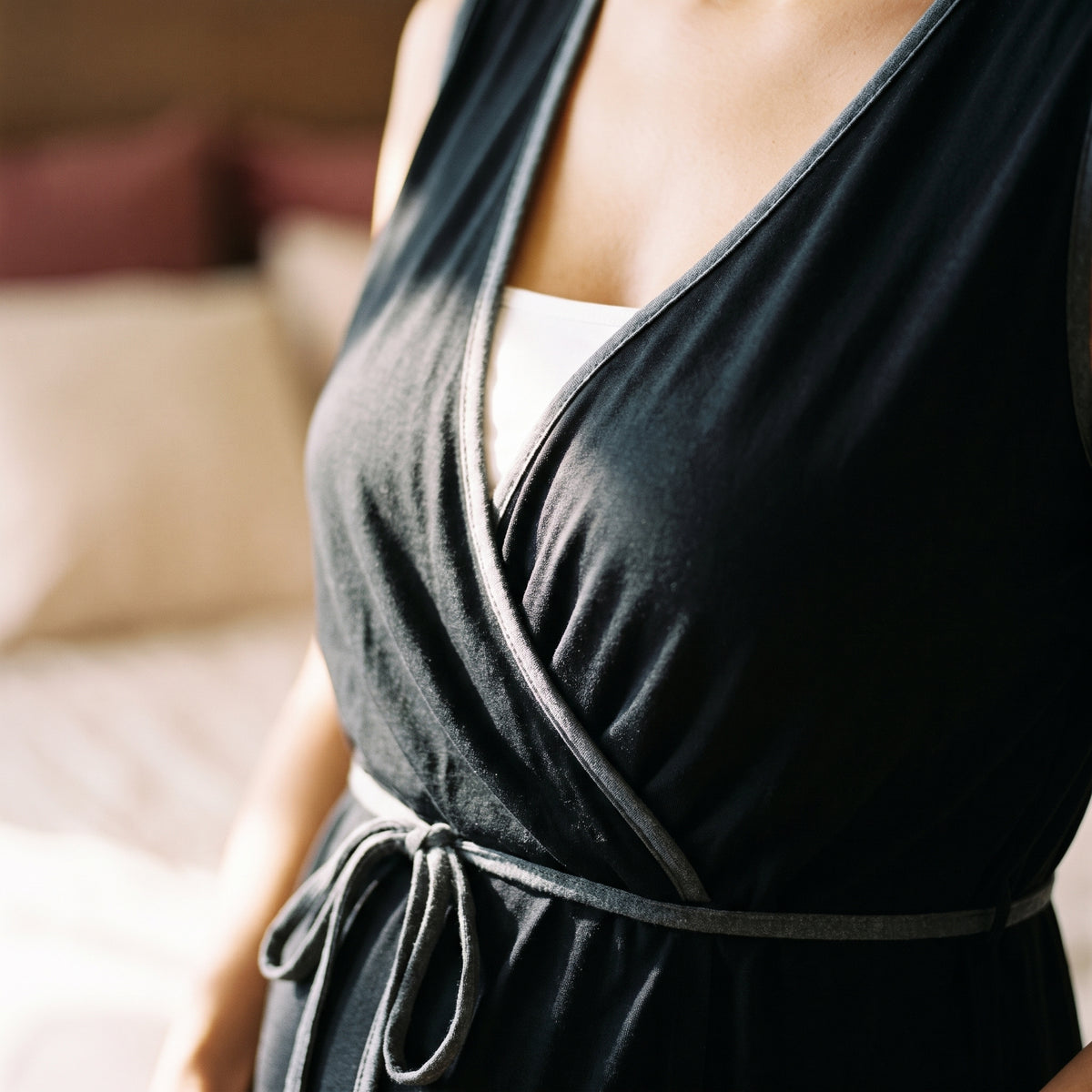 Gros plan sur le liseré gris et le décolleté croisé de la nuisette d'allaitement noire