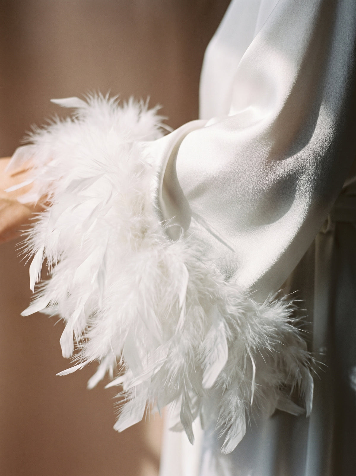 Gros plan sur les plumes vaporeuses des poignets de la robe de chambre blanche