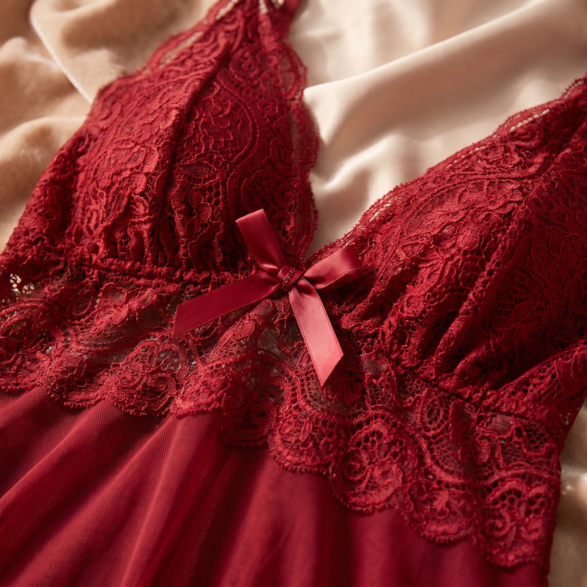 Détail de la dentelle florale et du nœud satiné de la nuisette rouge