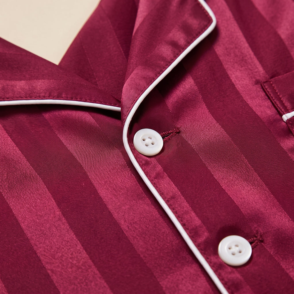 Gros plan sur le col tailleur, le passepoil blanc contrastant et les boutons du pyjama homme satin bordeaux