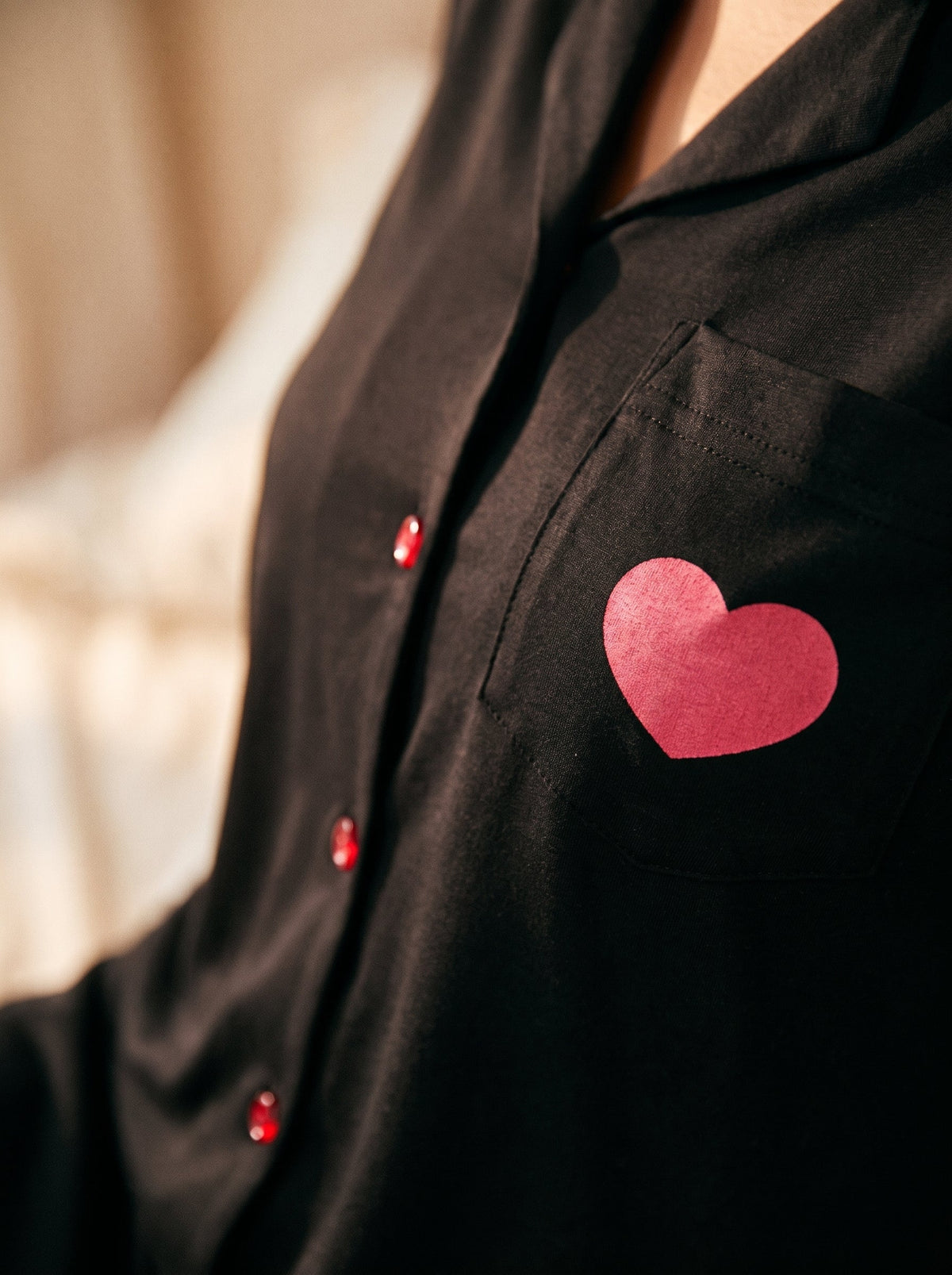 Gros plan poche poitrine chemise de nuit noire, cœur rose imprimé et boutons rouges