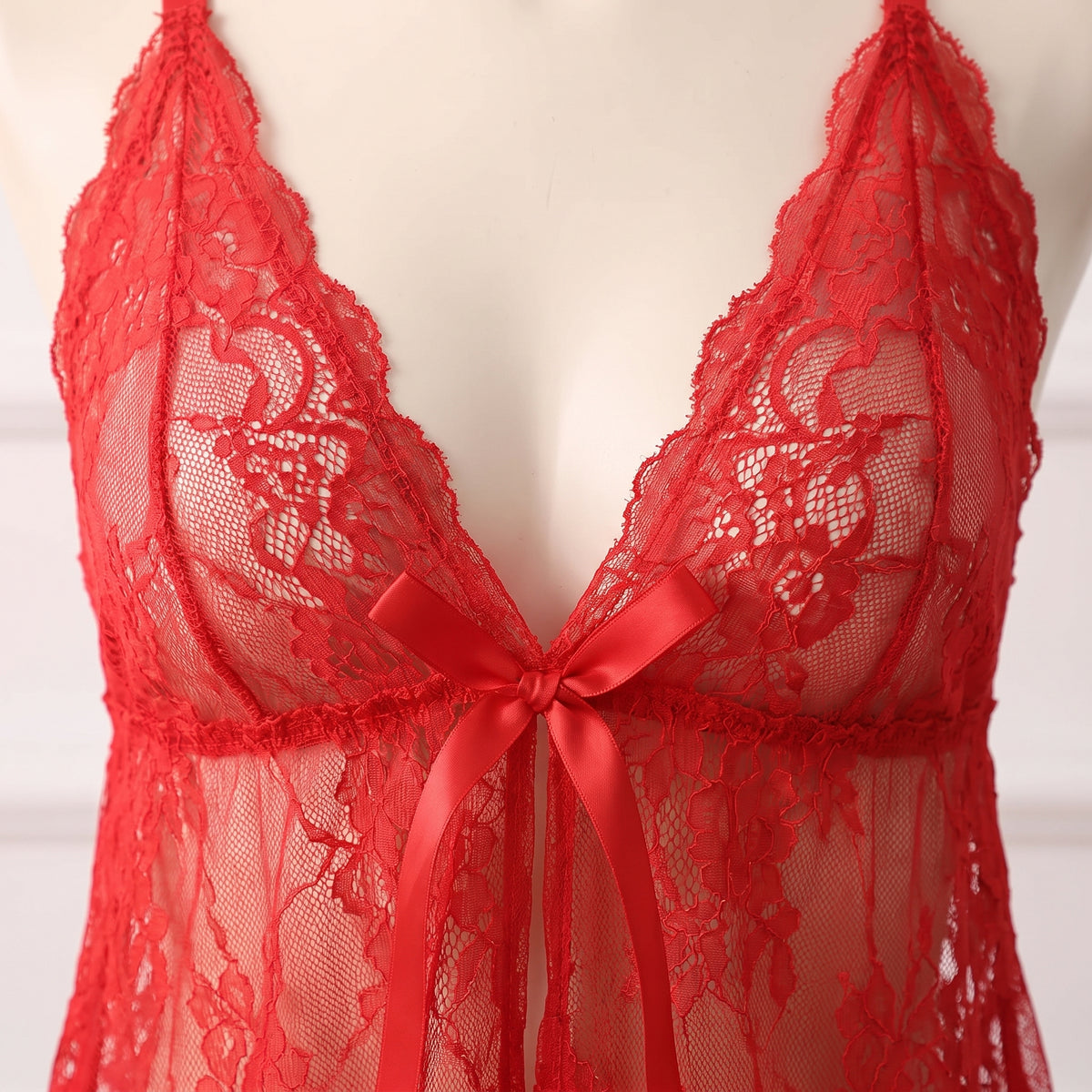 Détail des bonnets en dentelle florale rouge et du noeud satin qui ferme le buste
