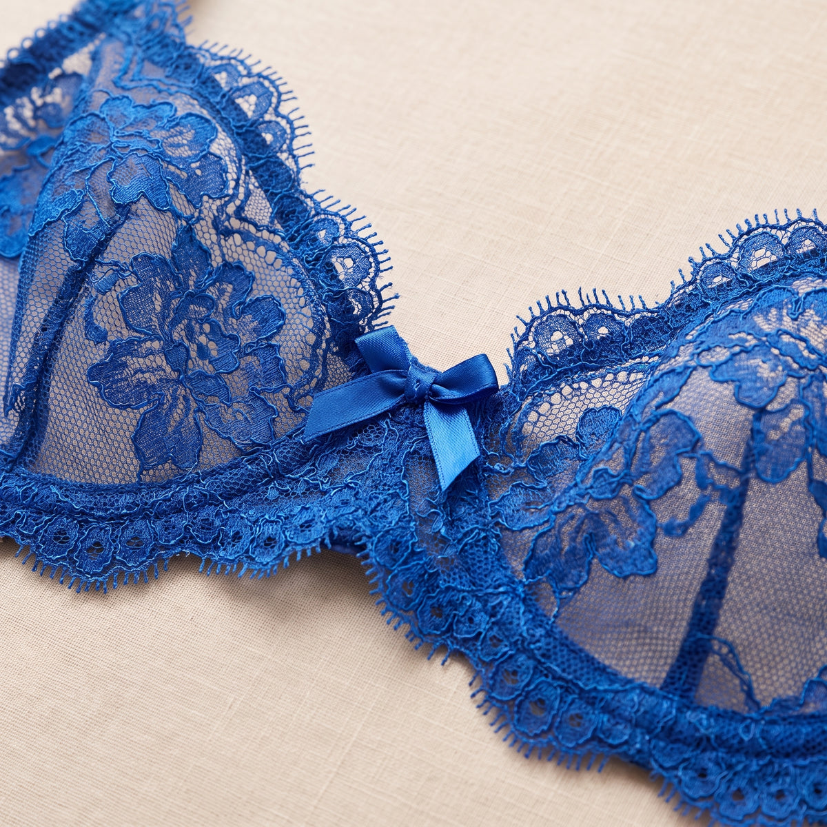 Détail des bonnets en dentelle florale bleu roi et du noeud satin
