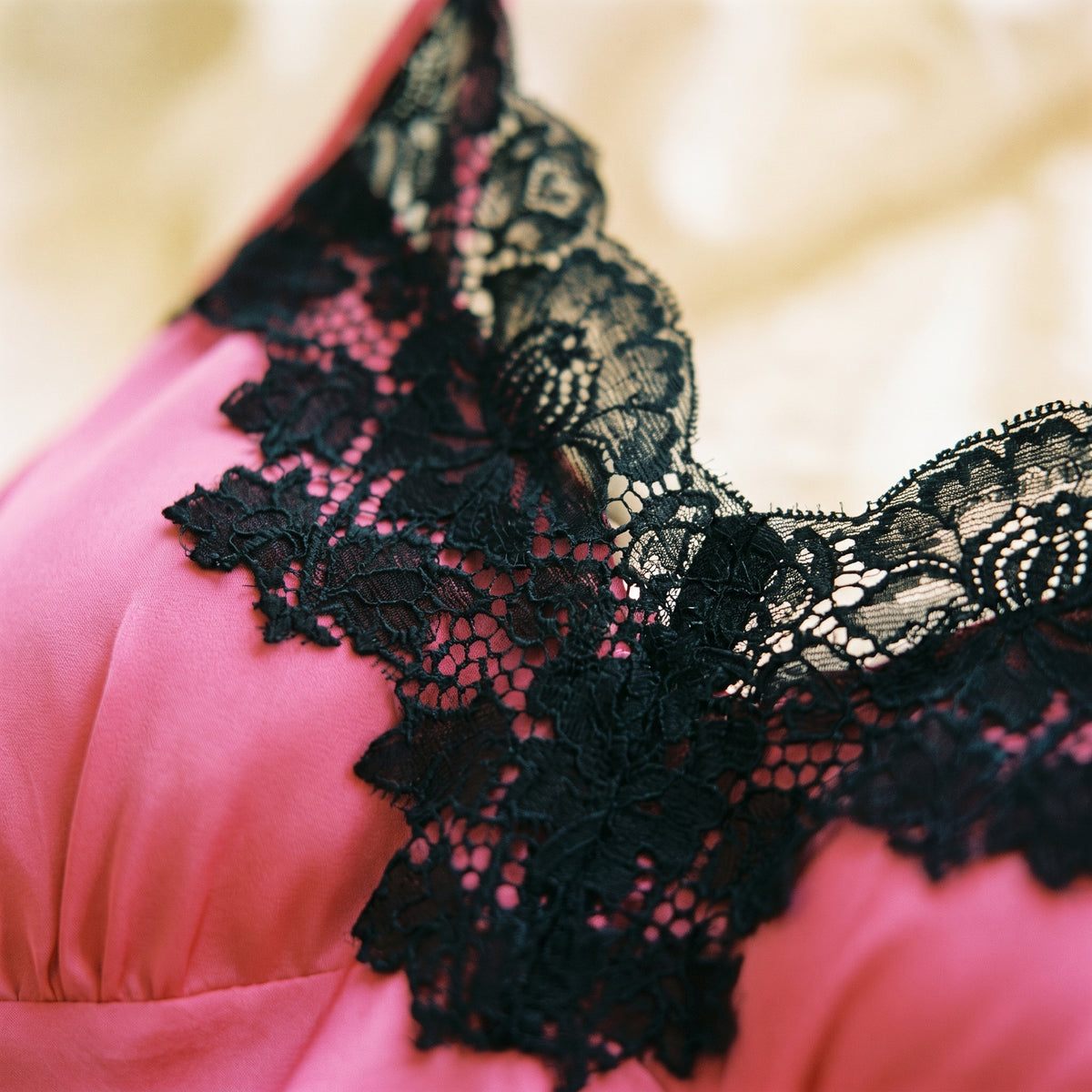 Gros plan sur la dentelle florale noire contrastant avec le satin rose fuchsia