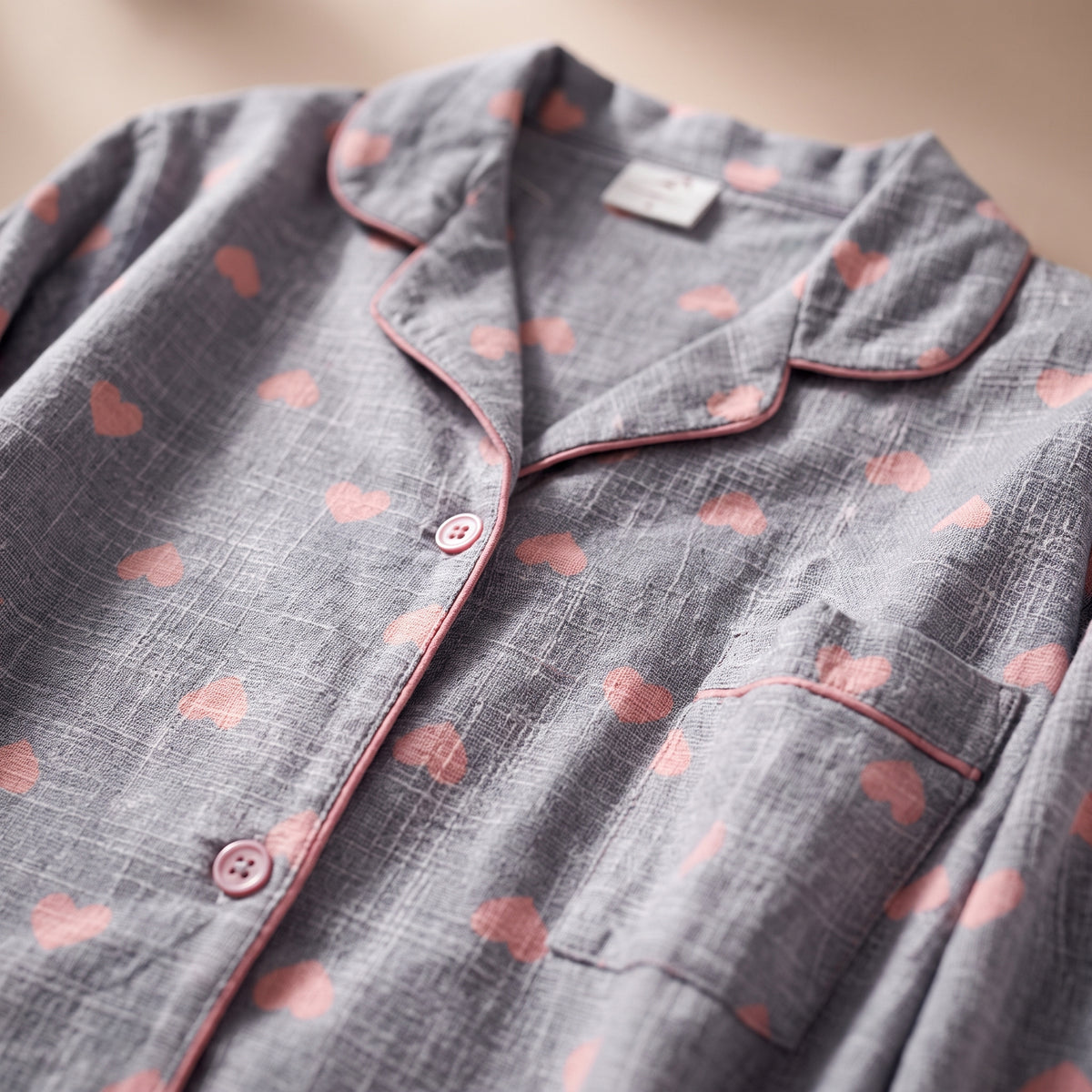 Gros plan sur le col tailleur, les boutons roses, la poche et l'imprime coeurs