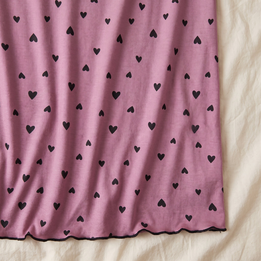 Semis de petits cœurs noirs sur la maille vieux rose, et bas de la robe fini d’un liseré noir ondulé