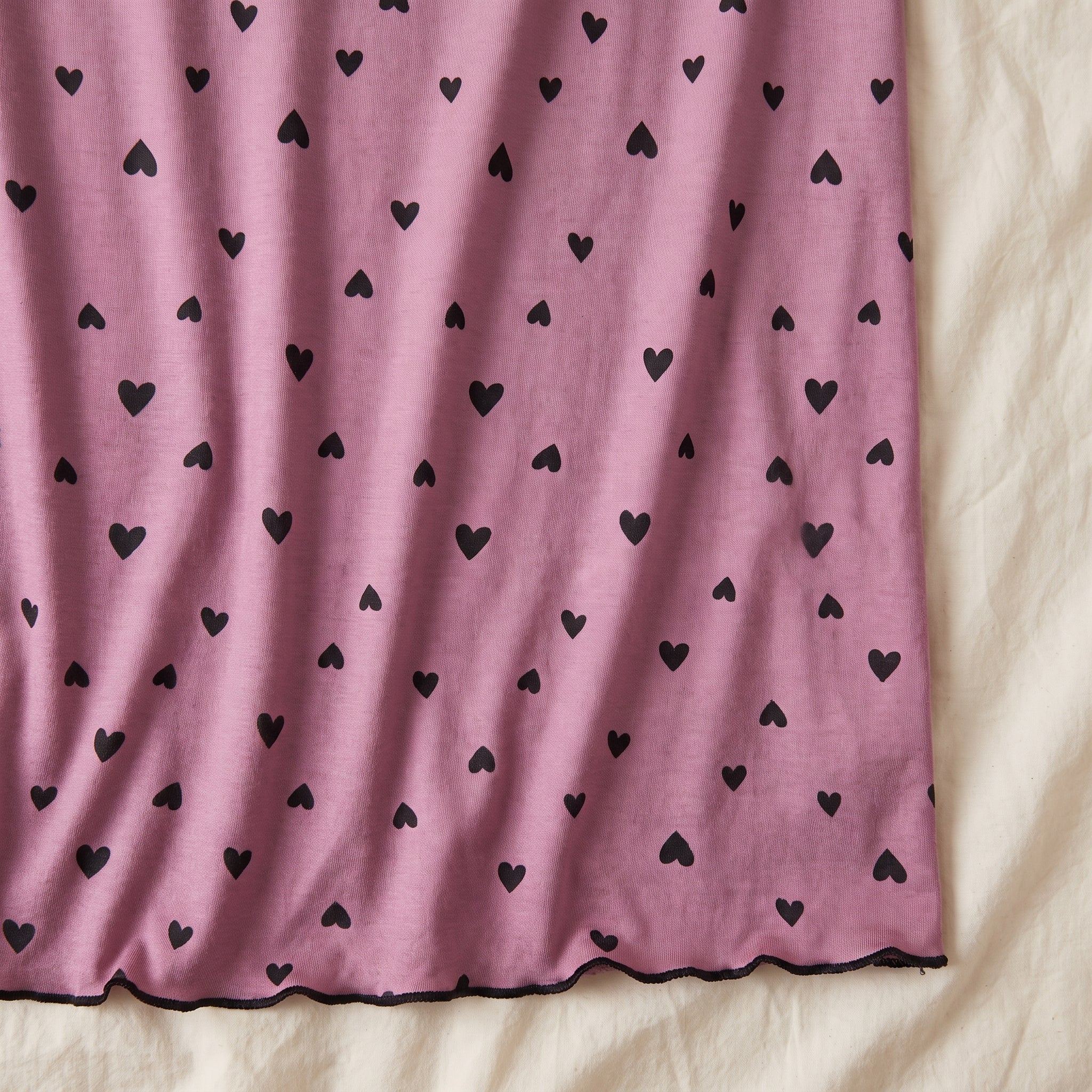 Semis de petits cœurs noirs sur la maille vieux rose, et bas de la robe fini d’un liseré noir ondulé Image