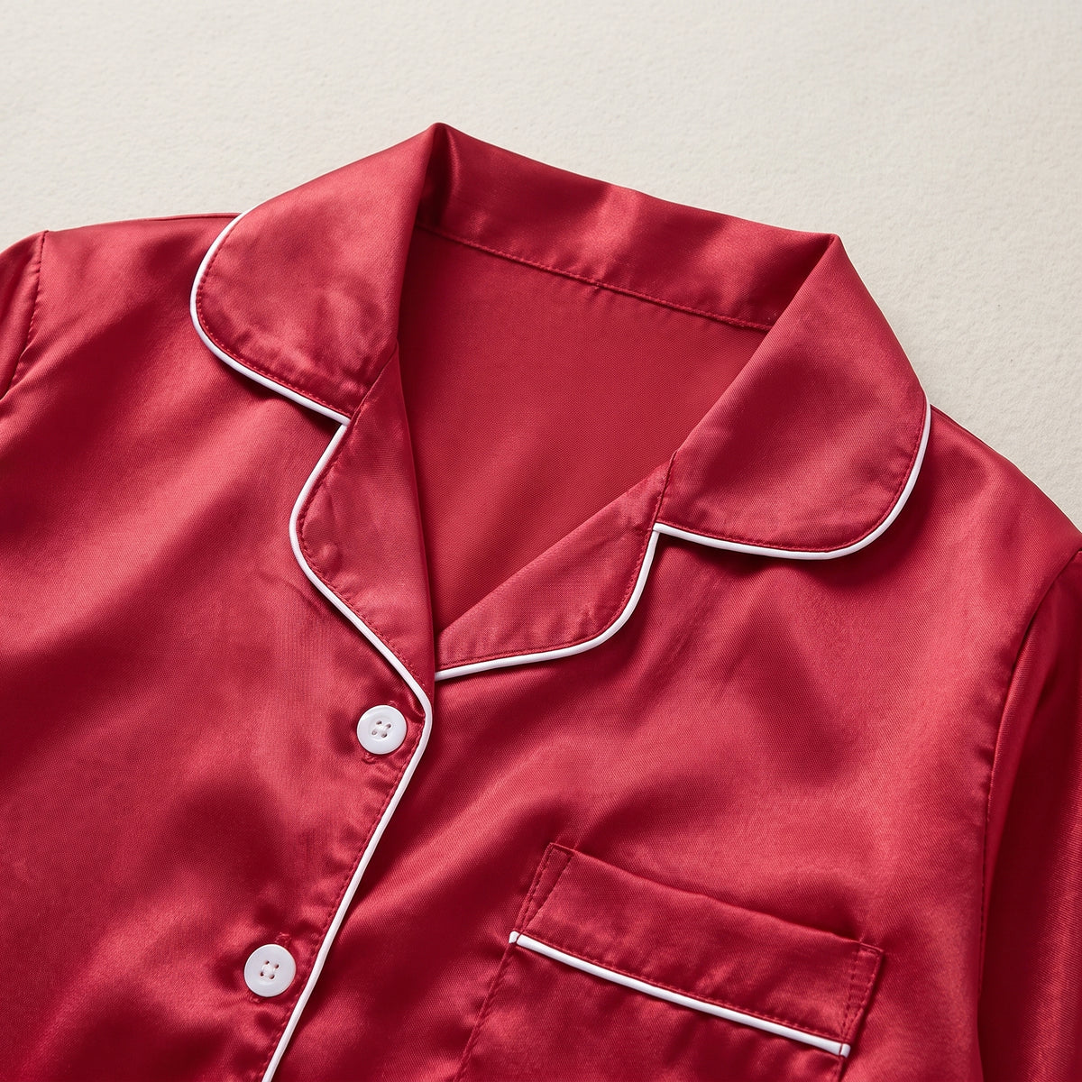 Détail du col cranté et de la poche à passepoil contrastant du pyjama fille en satin