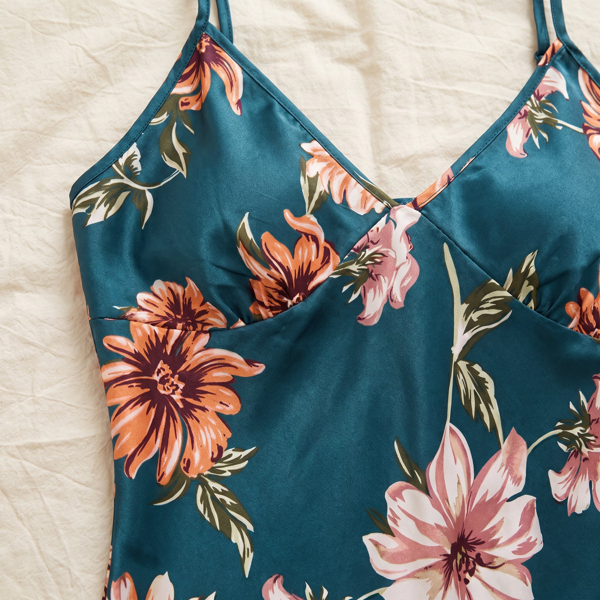 Décolleté en V du caraco et chrysanthème orange de l’imprimé vus de très près sur le satin