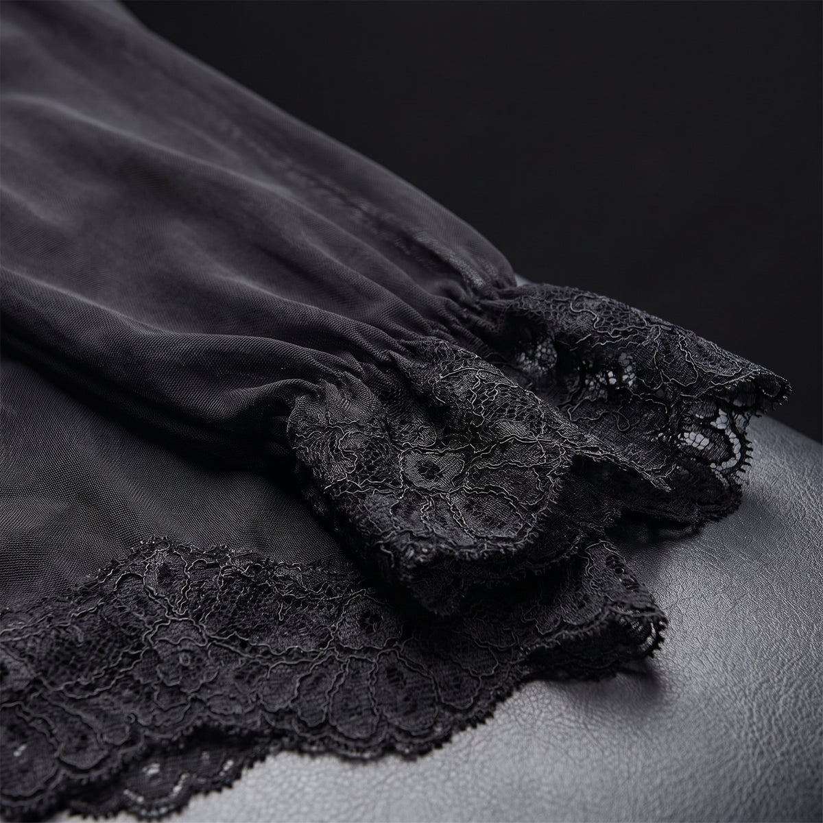 Détail du poignet et de l'ourlet en dentelle noire sur voile transparent