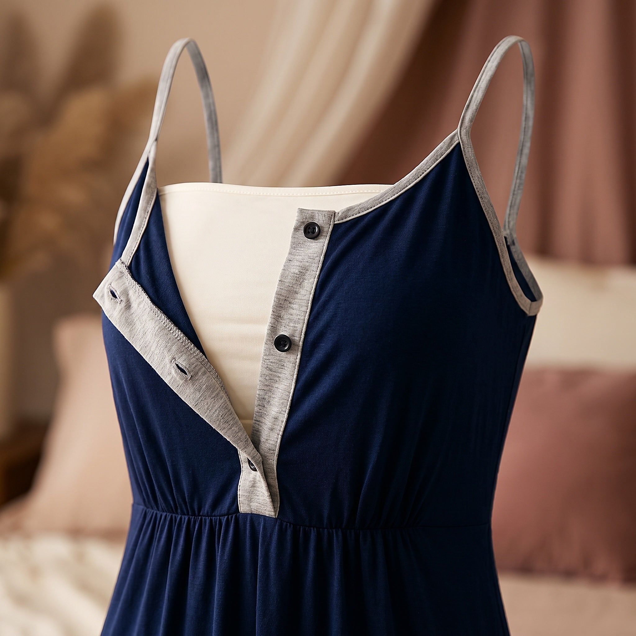 Nuisette d’allaitement bleue présentée sur mannequin invisible, patte déboutonnée et panneau écarté sur la doublure crème, le geste de la tétée Image