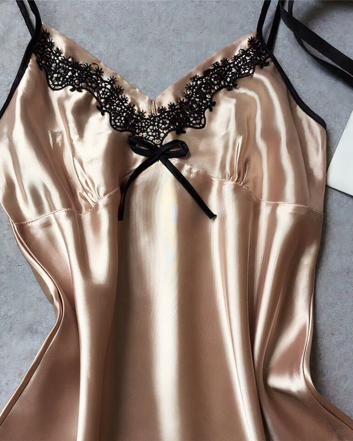 Détail du décolleté en V et du nœud noir de la nuisette beige