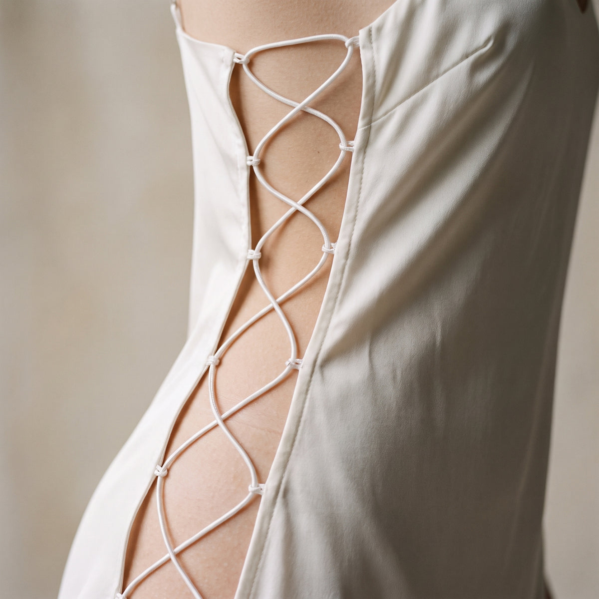 Gros plan cordons blancs croises et flanc ajoure de la nuisette blanche en satin