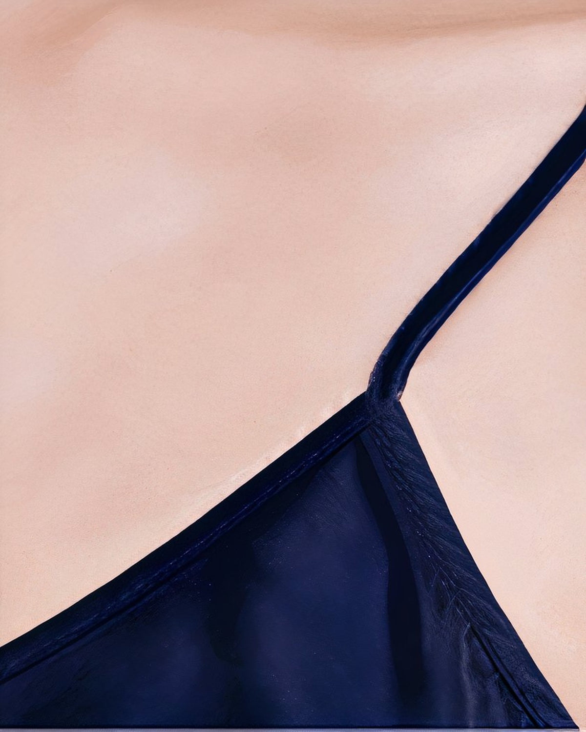 Detail rapproche du tissu satin bleu nuit de la nuisette, bretelles spaghetti et texture brillante