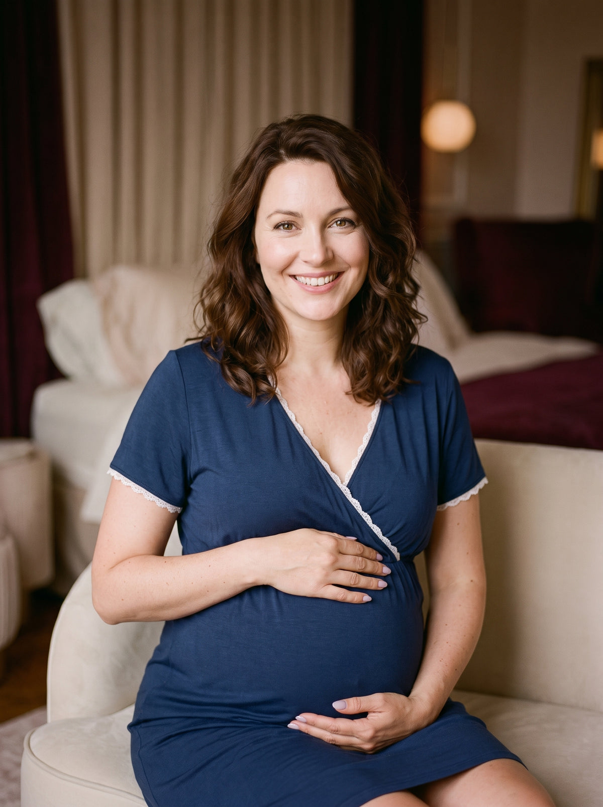 Femme enceinte souriante portant la nuisette grossesse bleu nuit dans un boudoir