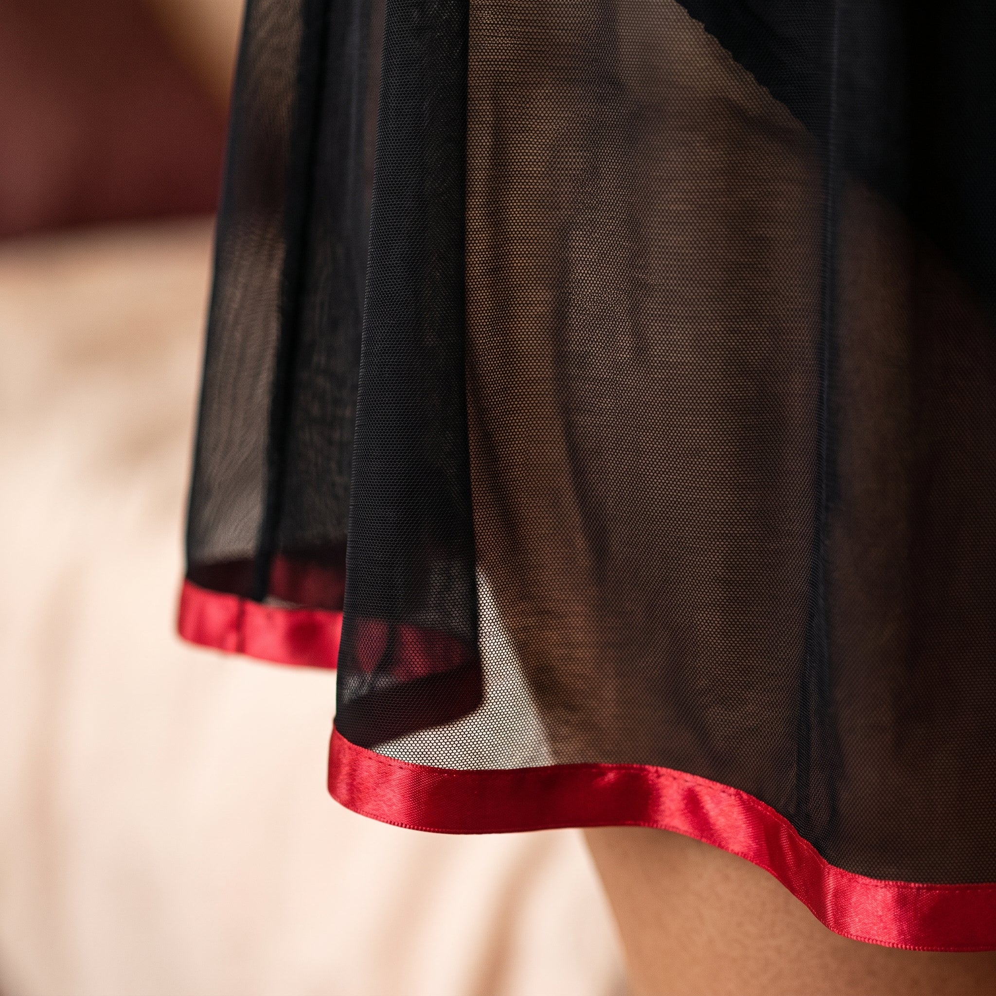 Détail du tulle noir transparent et de l'ourlet en satin rouge de la nuisette Image