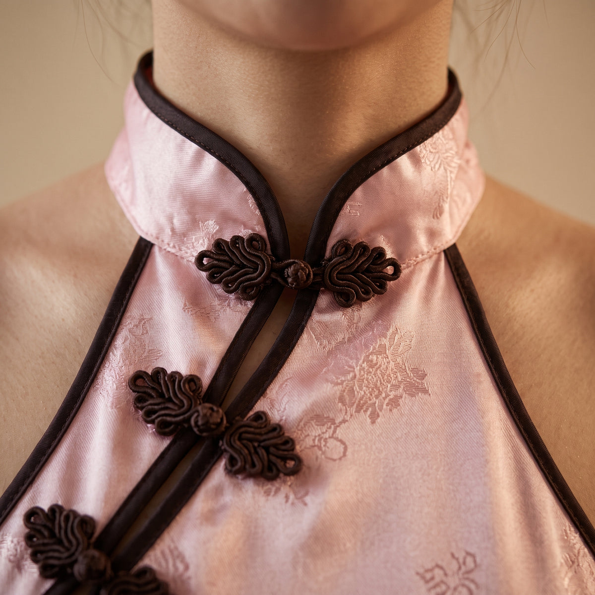 Col mandarin et boutons chinois de la nuisette en satin rose, gros plan macro