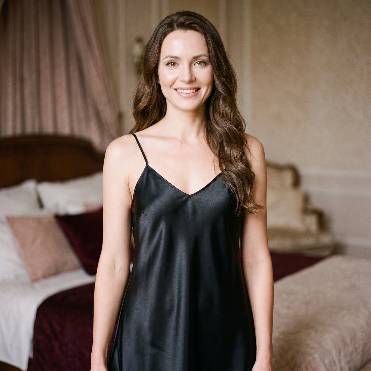 Modèle souriante portant la nuisette noire satinée dans une ambiance boudoir