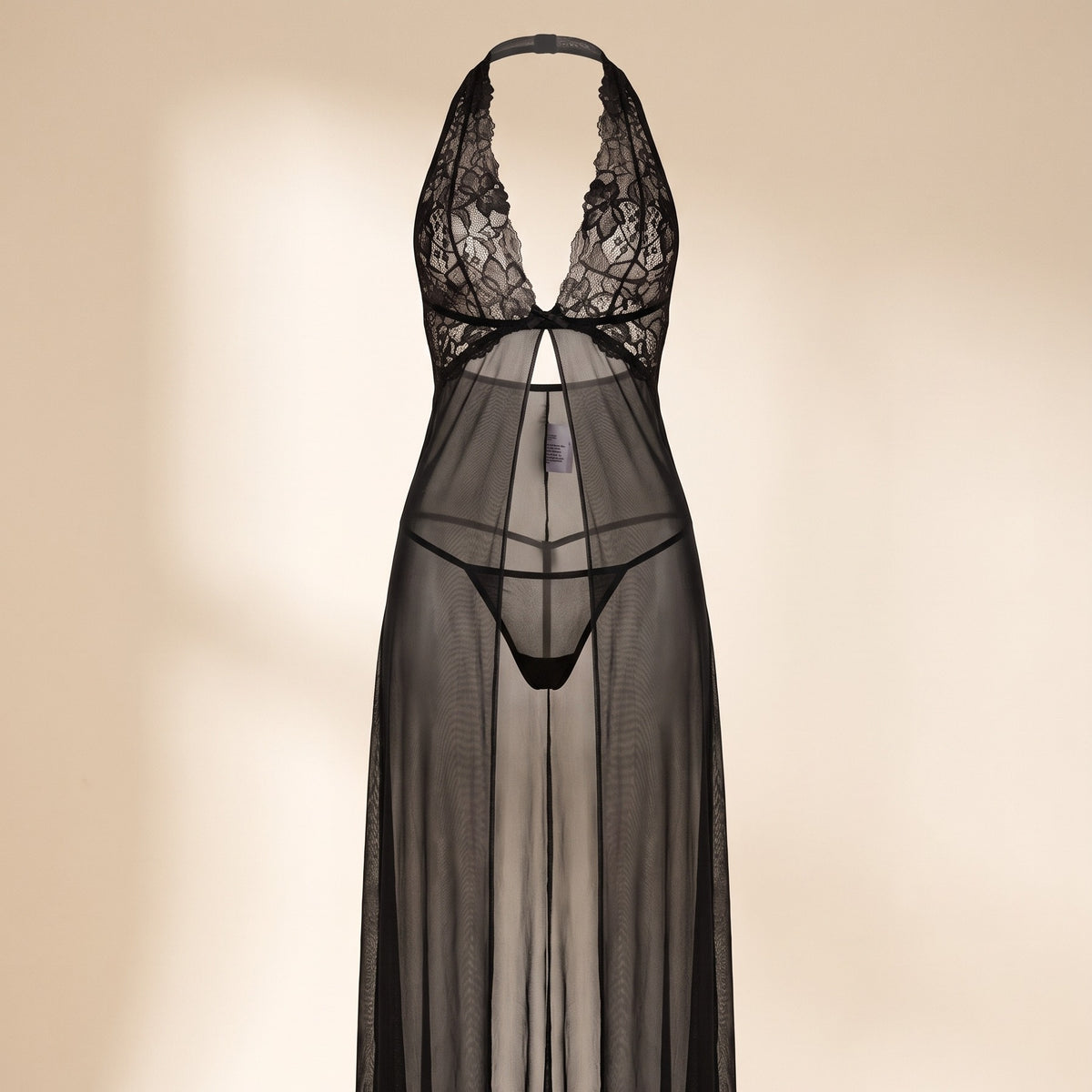 Gros plan buste de la nuisette longue noire, dentelle florale et décolleté en V sur fond boudoir