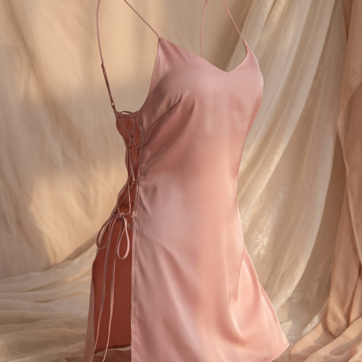 Nuisette rose ajourée portée sur mannequin invisible, vue de face, laçage croisé latéral visible Image