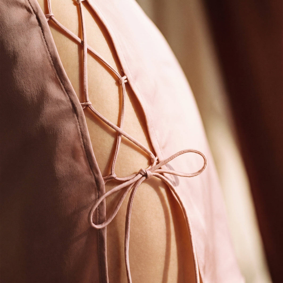 Détail macro du laçage croisé et du nœud délicat de la nuisette rose