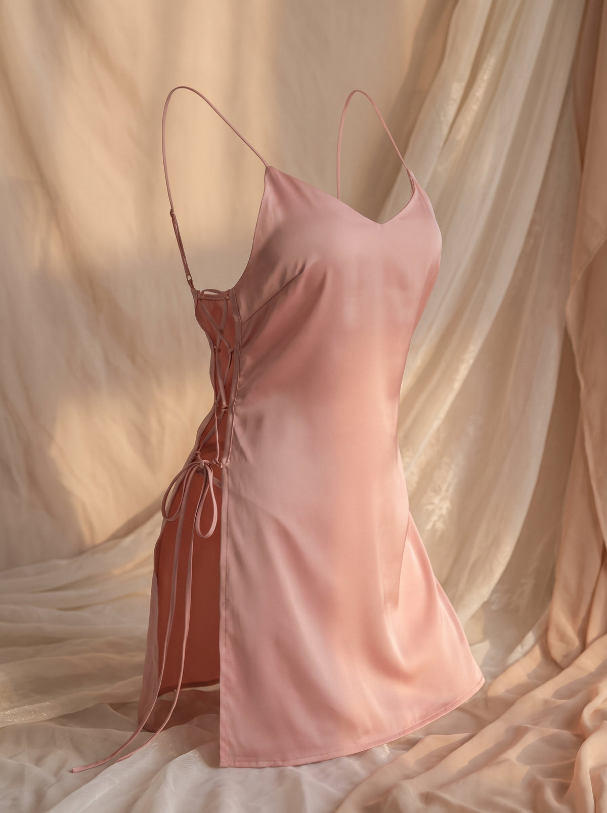 Nuisette rose ajourée portée sur mannequin invisible, vue de face, laçage latéral visible