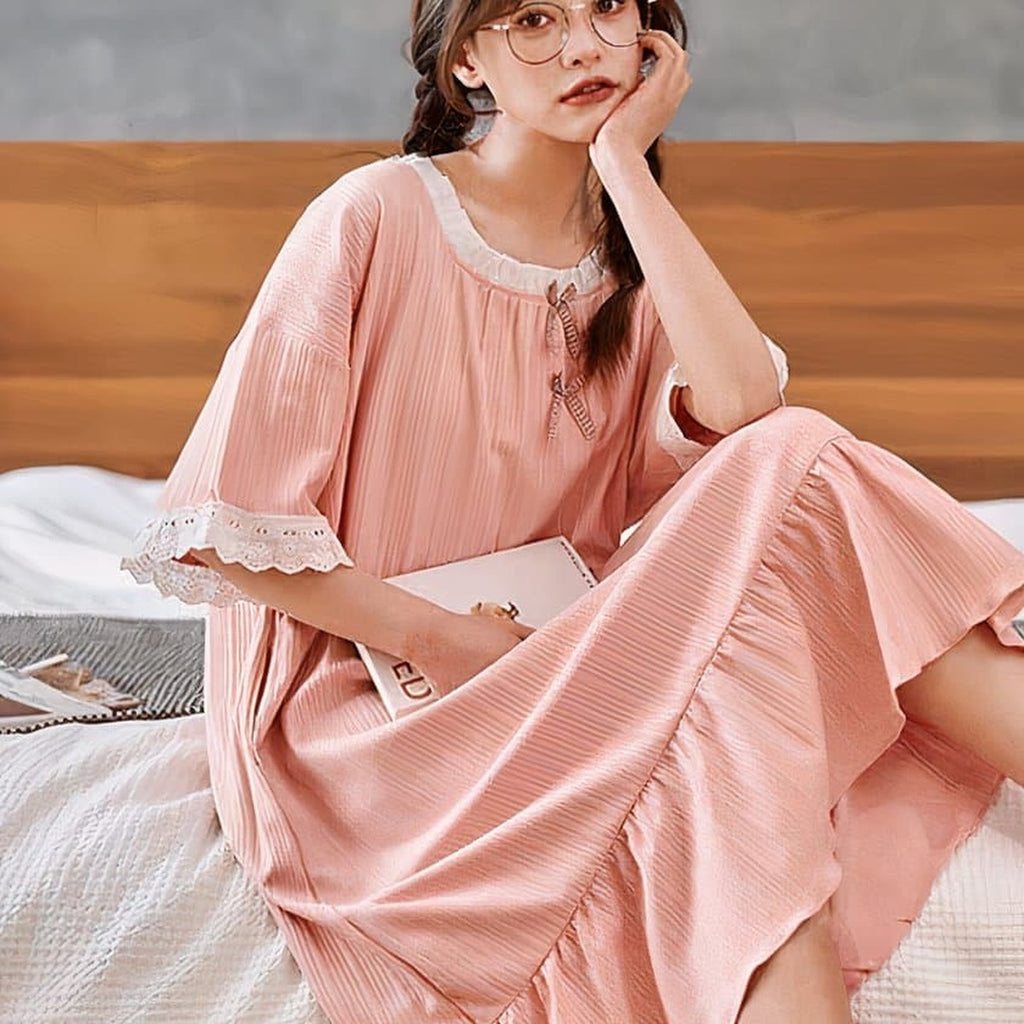 Modèle allongée sur un lit, nuisette rose en coton, ambiance douce et féminine