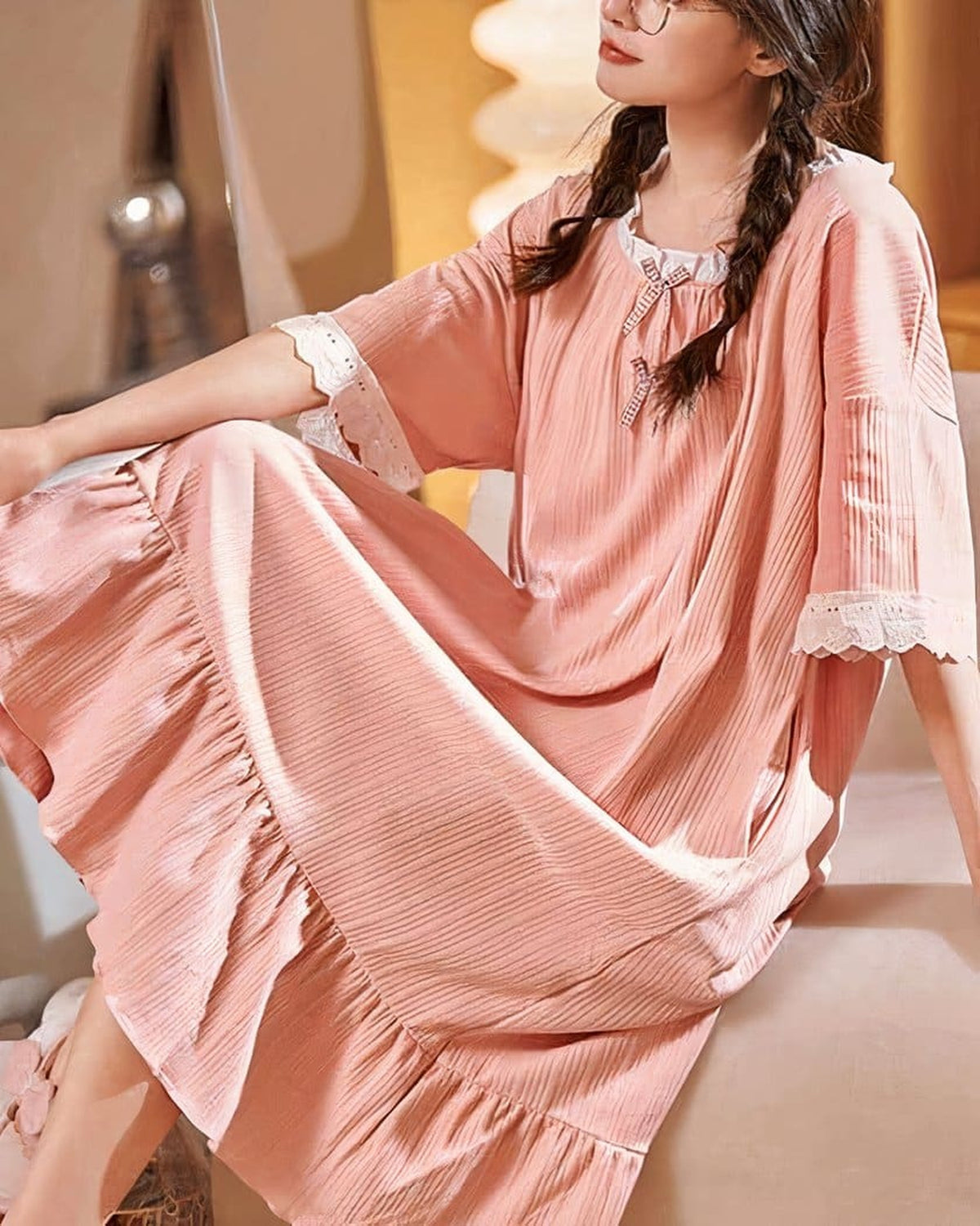 Nuisette rose en coton portée de trois-quarts, modèle assise, dentelle et noeuds vichy visibles