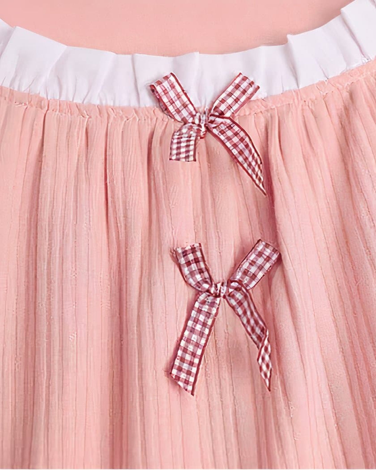 Gros plan sur la dentelle blanche et les noeuds vichy de la nuisette rose en coton