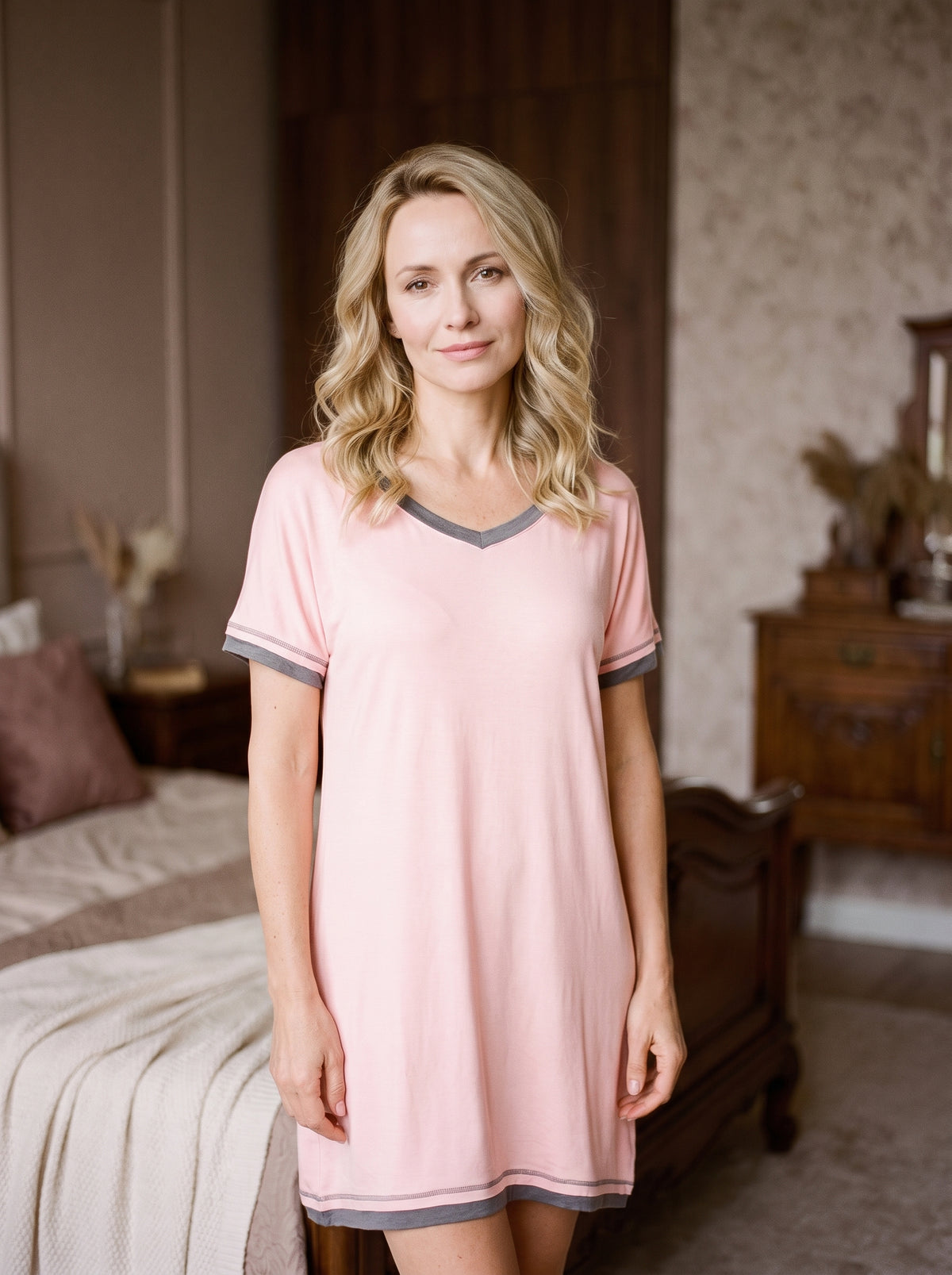 Modele portant la nuisette manche courte rose a bordures grises, col V, souriante dans un boudoir