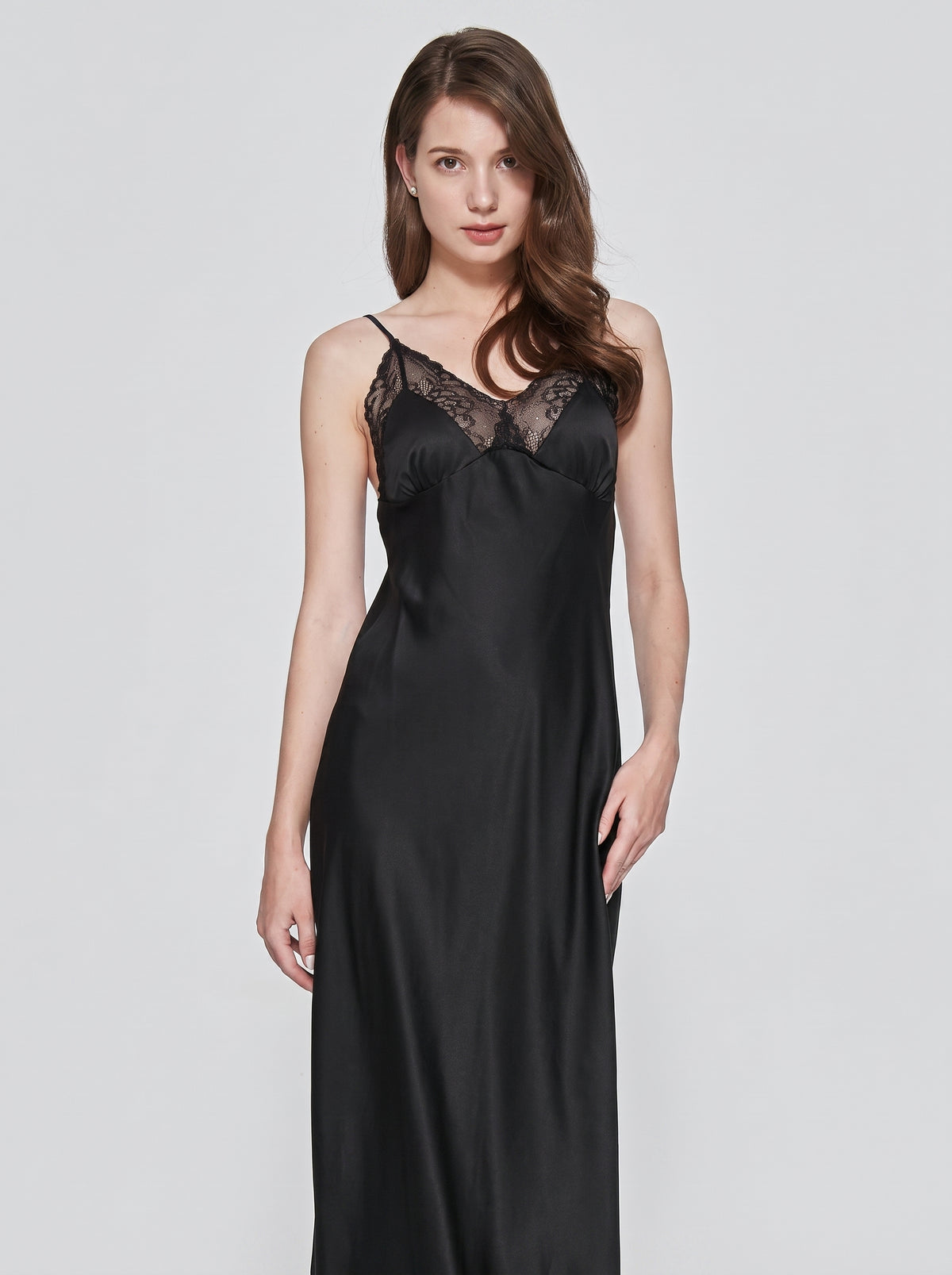 Nuisette longue noire en satin portee de face, tombe fluide du tissu